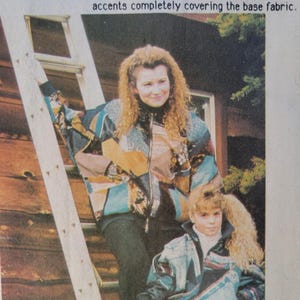 May include: Two people wearing colourful jackets with denim and leather accents. The jackets have a patchwork design with blue, teal, and yellow patterns. The text on the image reads "Our Tropical Towel Coat" and "Navy mirage bombers".