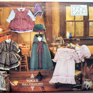 Puede incluir: Un sobre de patrón de costura Vogue Craft 8337 para una colección de muñecas. El frente muestra ilustraciones de varios conjuntos para muñecas, incluyendo un vestido rojo floral, una capa verde con sombrero, un vestido negro y un vestido rosa con volantes.