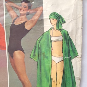 May include: Vintage sewing pattern featuring two women's clothing designs. The first design is a black swimsuit with a scoop neck. The second design is a green robe with a white bikini top and bottom underneath.