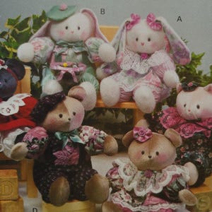 May include: A selection of handmade plush toys, featuring bunnies and bears. The toys are dressed in floral patterned fabrics and lace, in soft pastel colours. Some have hats and bows, creating a whimsical and vintage aesthetic.