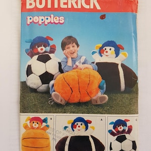 May include: A vintage sewing pattern for making Popples plush toys. The pattern is for a basketball, football, and soccer ball Popple. The pattern is from Butterick and is size one. The pattern cover features a child sitting on a basketball Popple.
