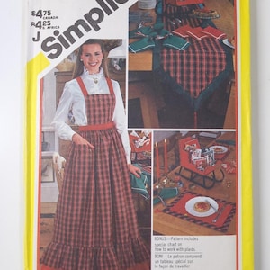 Op de afbeelding: Simplicity naaipatroonpakket met een vrouw in een rood-zwarte geruite jurk en een witte blouse. De verpakking bevat afbeeldingen van geruite tafeldecoraties. Tekst op de verpakking is onder meer "Pattern/Patron" en "Bonus - Pattern includes special chart on how to work with plaids."