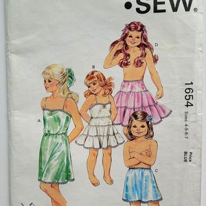 May include: Vintage Kwik Sew pattern 1654 featuring illustrations of children's clothing designs. The pattern includes sizes 4-5-6-7. The cover displays a green dress, a white dress, a pink skirt, and a blue skirt.