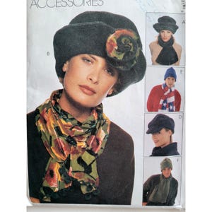 May include: A fashion pattern cover featuring a woman wearing a dark gray hat with a floral accent and a scarf with a floral pattern. Additional images show various hats and scarves, including a blue beanie and a newsboy cap. The word "ACCESSORIES" is at the top.