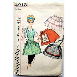 Puede incluir: Patrón de costura vintage Simplicity 4213 para delantales. La portada presenta a una mujer con un delantal verde a cuadros con bolsillos. Otros diseños de delantales incluyen un delantal rojo con un árbol de Navidad y un delantal a rayas. El patrón es talla única.