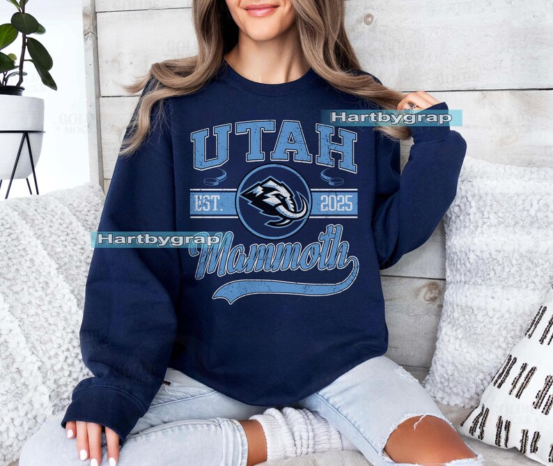 May include: Navy blue sweatshirt with a light blue graphic that reads "UTAH Mammoth 2025". The graphic includes a stylized mammoth logo. The sweatshirt is a crew neck style.