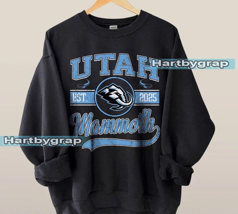 May include: Black crewneck sweatshirt with the text "UTAH Mammoth" in light blue. The design includes a circular emblem with an elephant graphic and the year "2025". The sweatshirt has a vintage, distressed look.