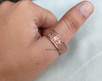 Könnte beinhalten: Ein kupferfarbener Ring mit floralem und geometrischem Muster. Der Ring wird an einem Finger getragen. Der Text "925Silvergems2026" ist auf dem Ring zu sehen.