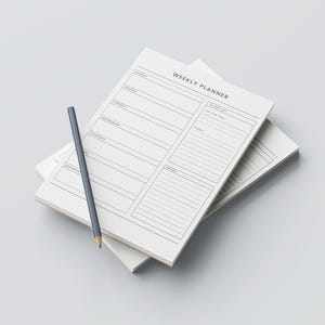 Peut inclure: Une pile de blocs-notes hebdomadaires blancs avec un crayon gris. Le bloc-notes supérieur porte l'inscription "WEEKLY PLANNER". Le planificateur comporte des sections pour chaque jour de la semaine, une liste de tâches et des notes. Le crayon repose sur le bloc-notes.