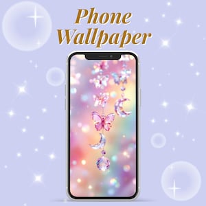 Op de afbeelding: Een smartphone toont een telefoonachtergrondontwerp. De achtergrond heeft een dromerige, pastelkleurige achtergrond met hangende vlinders, manen en een kristal. De woorden "Phone Wallpaper" zijn in goud.