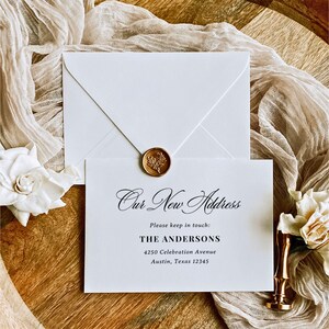 May include: A white envelope sealed with a gold wax seal featuring a floral design, paired with a white card printed with the text Our New Address, Please keep in touch: THE ANDERSONS, 4250 Celebration Avenue, Austin, Texas 12345.