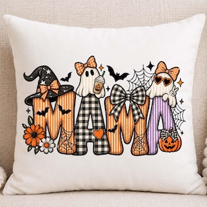 May include: A white square throw pillow featuring the word MAMA in large, patterned letters. The design includes ghosts, a witch hat, pumpkins, spiderwebs, bats, flowers, and bows in orange, black, white, and purple colors on the letters.