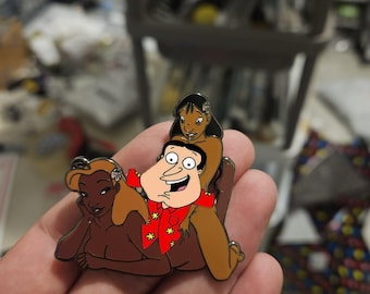 May include: A metal enamel pin featuring a cartoon character with dark hair wearing a red shirt with yellow flower patterns, positioned between two animated figures with long brown hair, one wearing a white flower in their hair, all in a group.
