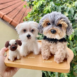 May include: Three crocheted dog figurines of varying sizes, displayed on a wooden tray. The smallest is 5 cm, the middle is 10 cm, and the largest is 15 cm. The dogs have different colors and patterns, including white, brown, and grey.