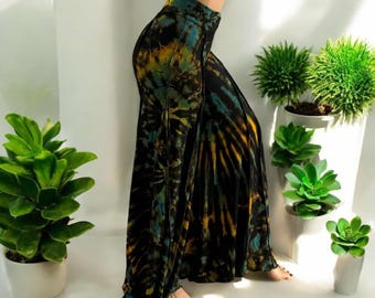 Könnte beinhalten: Weite Hose mit Batikmuster in Schwarz, Gelb und Türkis. Die Hose hat eine hohe Taille und eine fließende Silhouette. Das Model trägt ein schwarzes Crop-Top. Die Hose ist für Freizeitkleidung geeignet.