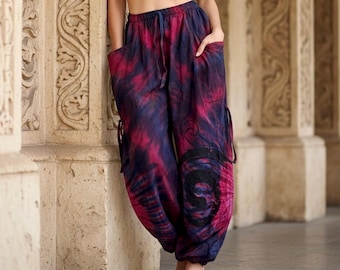 May include: Loose-fitting trousers featuring a vibrant tie-dye pattern in shades of deep magenta and dark navy blue. These pants include an elasticized waistband with a drawstring, side pockets, and a prominent black spiral graphic on the lower leg.