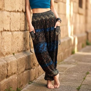 May include: Loose-fitting trousers featuring a black base with intricate gold and blue paisley patterns. These trousers have a wide, elasticated waistband, side pockets with drawstring details, and gathered cuffs at the ankles for a relaxed fit.