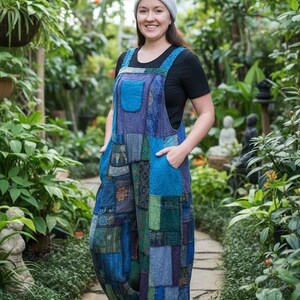 Może przedstawiać: Niebieskie ogrodniczki w stylu patchwork z dużą przednią kieszenią i regulowanymi ramiączkami. Ogrodniczki mają różnorodne niebieskie, zielone i fioletowe łaty materiału. Widoczny jest również czarny t-shirt i szara czapka.