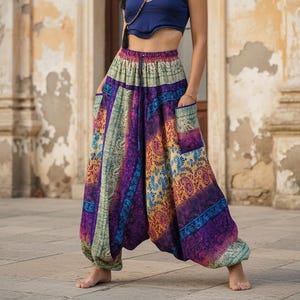 May include: Loose-fitting harem pants featuring a vibrant, multi-colored paisley pattern in shades of purple, orange, teal, and cream. These wide-leg trousers have an elasticized high waistband, a dropped crotch, and two large side pockets.