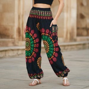 Puede incluir: Pantalones har&eacute;n negros con coloridos dise&ntilde;os de mandala en rojo, verde y amarillo. Los pantalones tienen un ajuste holgado y bolsillos. Se llevan con sandalias blancas. Miden aproximadamente 100 cm de largo.