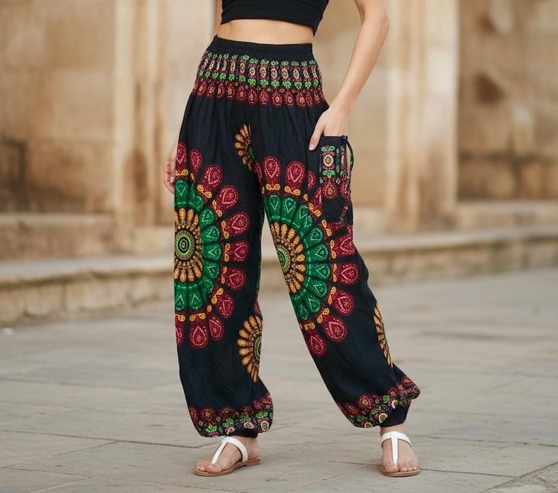 Puede incluir: Pantalones har&eacute;n negros con coloridos dise&ntilde;os de mandala en rojo, verde y amarillo. Los pantalones tienen un ajuste holgado y bolsillos. Se llevan con sandalias blancas. Miden aproximadamente 100 cm de largo.