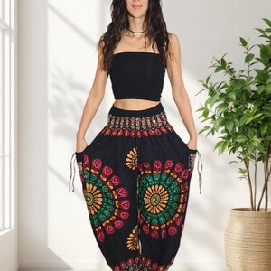 Puede incluir: Pantalones harem negros con un estampado floral colorido en rojo, verde y amarillo. Los pantalones tienen bolsillos con cord&oacute;n y se combinan con un top bandeau negro. Un atuendo casual y c&oacute;modo.