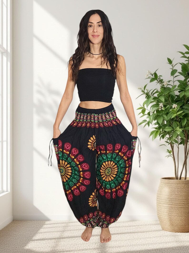 Puede incluir: Pantalones harem negros con un estampado floral colorido en rojo, verde y amarillo. Los pantalones tienen bolsillos con cord&oacute;n y se combinan con un top bandeau negro. Un atuendo casual y c&oacute;modo.