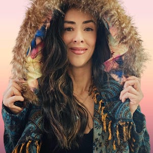 May include: A white ceramic mug with a black handle and the text "But First, Coffee" in a bold, black font. The mug is set against a blurred background, suggesting a cozy setting.