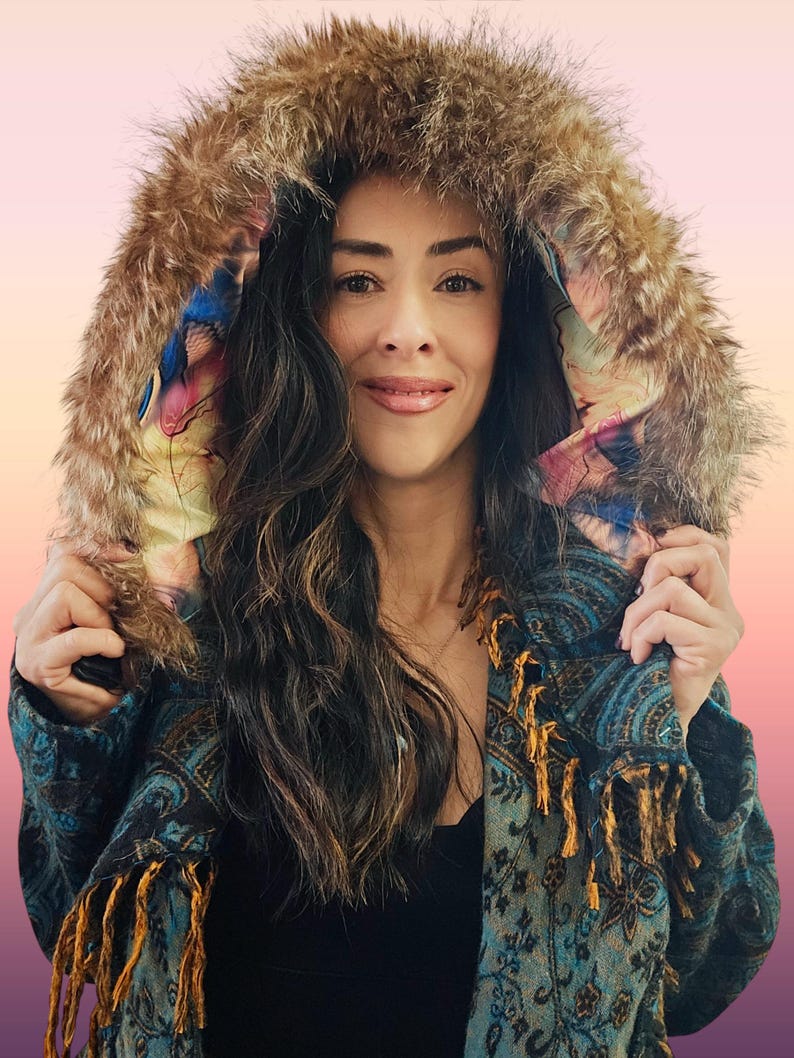 May include: A white ceramic mug with a black handle and the text "But First, Coffee" in a bold, black font. The mug is set against a blurred background, suggesting a cozy setting.