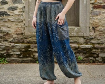 May include: Blue and gray patterned harem pants with a drawstring waist and pockets. The pants feature a gradient design, transitioning from gray at the top to blue at the bottom. The fabric has a floral-like pattern.