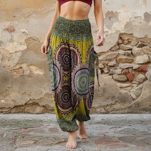 May include: Harem trousers with a vibrant, patterned design. The trousers have a yellow base, adorned with large, circular patterns in red, blue, and brown. They feature an elasticated waist and a loose, comfortable fit.