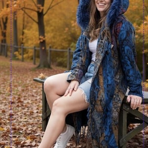 May include: A long-sleeved hooded coat featuring a deep blue and brown paisley pattern with a faux fur trim on the hood and fringe detailing at the hem. The coat is worn over a white top and light blue denim shorts, paired with white trainers.