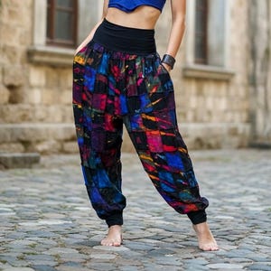 May include: Loose-fitting pants featuring a wide black waistband and a colorful patchwork pattern of blue, red, purple, and yellow squares. The pants have a relaxed silhouette with tapered cuffs at the ankles, creating a distinct gathered look.