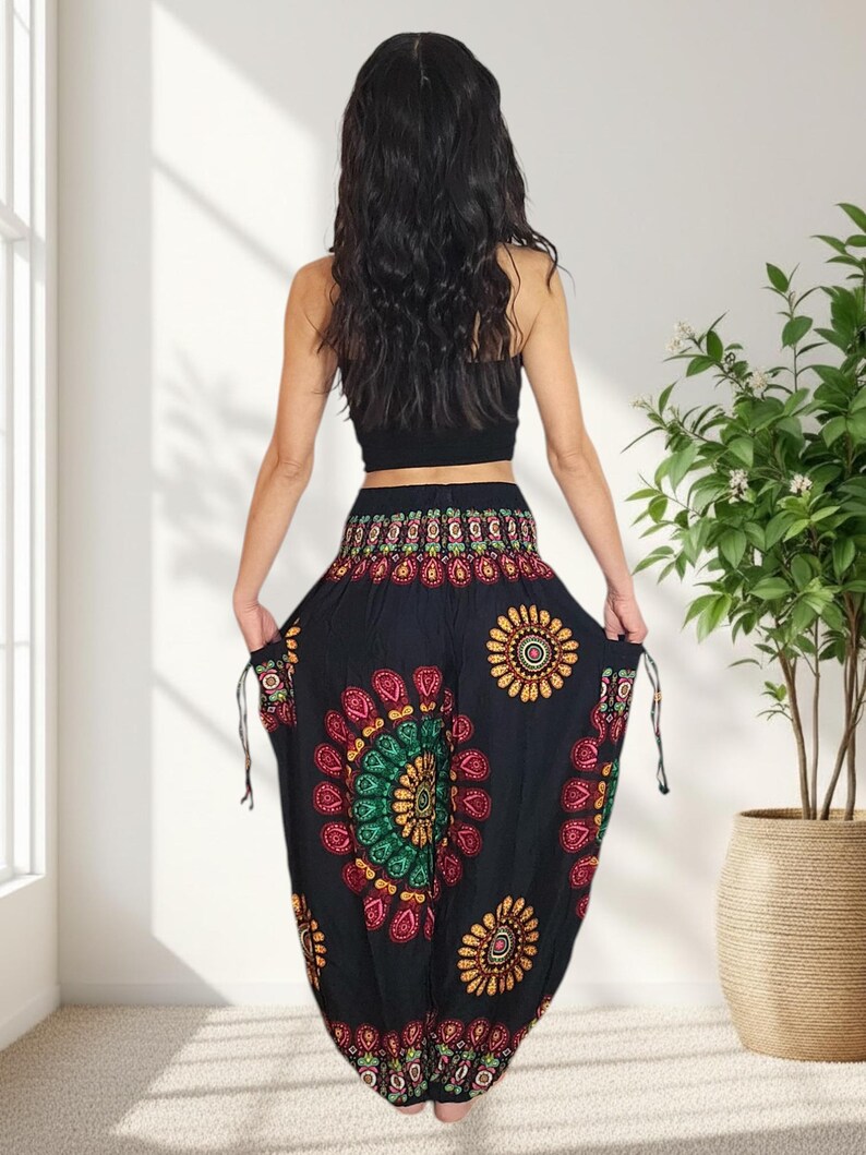 Puede incluir: Pantalones harem negros con un vibrante estampado floral en rojo, amarillo y verde. Los pantalones tienen cintura con cord&oacute;n y est&aacute;n hechos de tela ligera. La modelo lleva un top corto negro. Una opci&oacute;n c&oacute;moda y elegante.