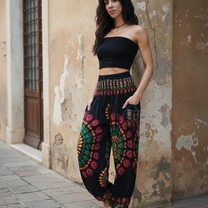 Puede incluir: Pantalones har&eacute;n negros con coloridos dise&ntilde;os de mandala en rojo, verde y amarillo. Los pantalones tienen bolsillos y se combinan con un top de tubo negro. La persona lleva chanclas blancas.