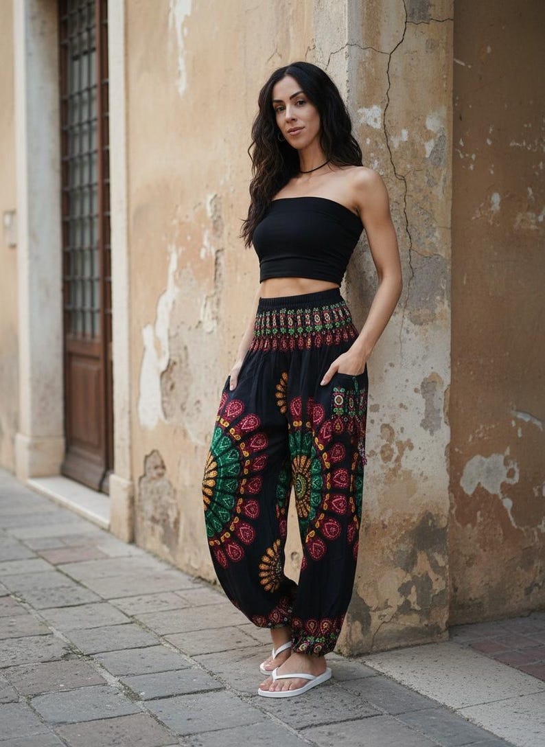 Puede incluir: Pantalones har&eacute;n negros con coloridos dise&ntilde;os de mandala en rojo, verde y amarillo. Los pantalones tienen bolsillos y se combinan con un top de tubo negro. La persona lleva chanclas blancas.