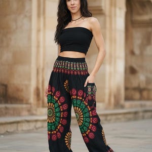 Puede incluir: Pantalones harem negros con un colorido dise&ntilde;o de mandala en rojo, verde y amarillo. Los pantalones tienen bolsillos y se combinan con un top de tubo negro. El conjunto es casual y bohemio.