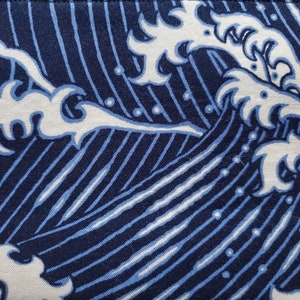 May include: Blue and white fabric with a repeating pattern of stylised waves. The waves are outlined in white and filled in with a light blue colour. The background is a dark blue colour.