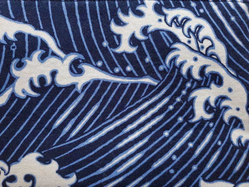 May include: Blue and white fabric with a repeating pattern of stylised waves. The waves are outlined in white and filled in with a light blue colour. The background is a dark blue colour.