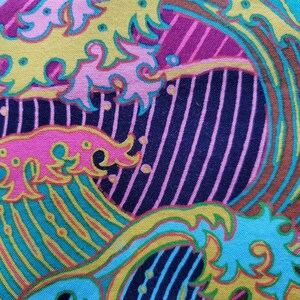 May include: Abstract fabric with a colourful wave pattern in shades of pink, yellow, blue, green, and brown. The fabric has a textured surface and a striped background.
