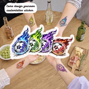 May include: A collection of temporary tattoo stickers featuring a soccer ball design with flames in various colors: blue, green, purple, and red. The text "2026 Word Cup" and "Mbapp" are visible on the stickers. The image also includes the text "Come design your own custom tattoo sticker."