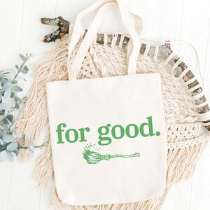 May include: Cream-colored tote bag with the phrase "for good." in green, along with a green broom graphic. The bag has long handles and is made of a sturdy fabric, perfect for carrying books or groceries.
