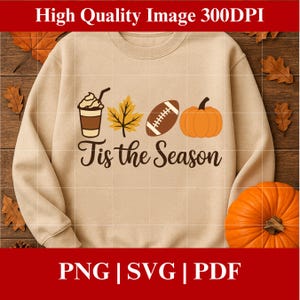 May include: Beige sweatshirt featuring a seasonal design. The graphic includes a coffee cup, a leaf, a football, and a pumpkin. The words "Tis the Season" are below the illustrations. The image also includes the text "High Quality Image 300DPI".