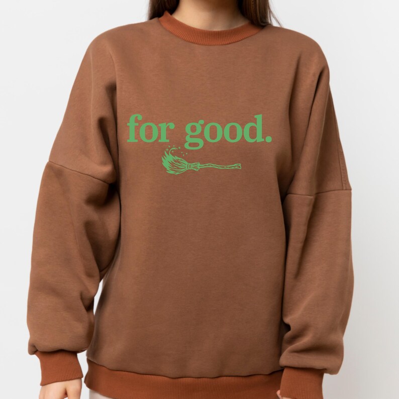 May include: Brown sweatshirt with the text "for good." in green, along with a green broom graphic. The sweatshirt has a brown collar and cuffs.