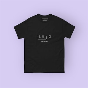 Puede incluir: Camiseta negra con un gráfico blanco de un diagrama de circuito y el texto "Trust the logic." La camiseta tiene cuello redondo y mangas cortas. El gráfico incluye los números 10.0, 10.1 y 00.0.