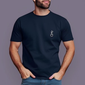 Puede incluir: Camiseta azul marino con un pequeño diseño gráfico blanco en el pecho, que representa un componente informático estilizado. La camiseta de manga corta tiene cuello redondo. La persona lleva vaqueros.