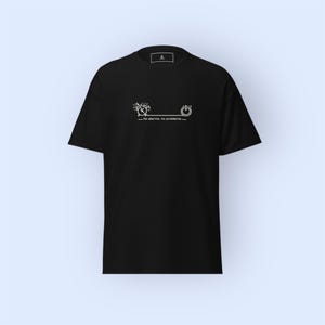 Op de afbeelding: Zwart t-shirt met een wit grafisch ontwerp met een wekker, een aan/uit-knop en de tekst "No alarms, no problems." Het shirt heeft een ronde hals en korte mouwen. Het ontwerp is gecentreerd op de voorkant.