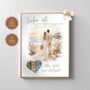 May include: Framed wedding art print featuring a couple on a beach at sunset. The print includes the text "Liebe ist...gemeinsam dem Horizont entgegenzugehen" and "Alles Gute zur Hochzeit!" A gold bow adorns the frame.