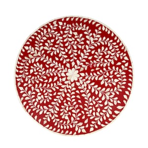 May include: Circular red table with a white floral inlay design. The table has a central flower motif and a border. The intricate pattern is made of white leaf-shaped pieces. The table is a decorative accent piece, approximately 76 cm in diameter.
