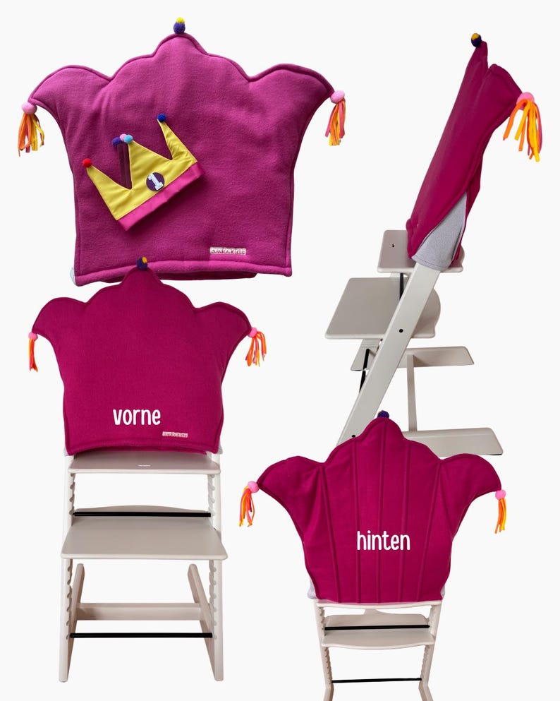 May include: A magenta crown-shaped high chair cushion with colorful tassels on the points, a small yellow crown accessory with the number one, and white text labels reading vorne and hinten on the cushion fabric.